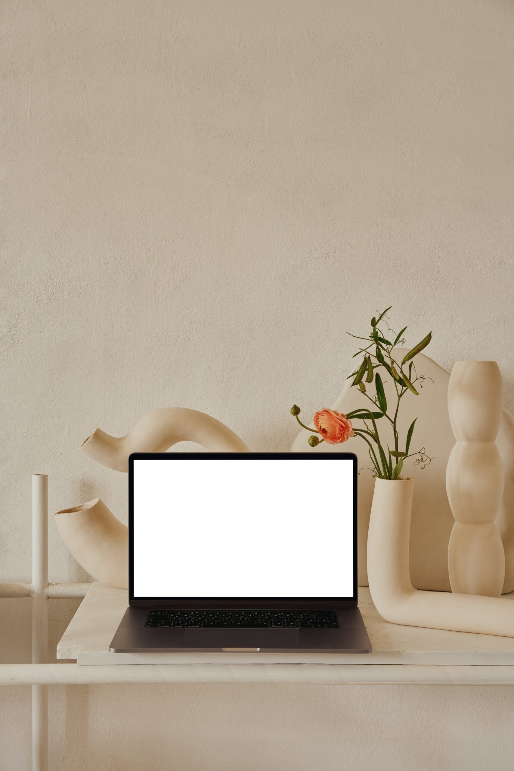 bureau blanc avec ordinateur ouvert et vases