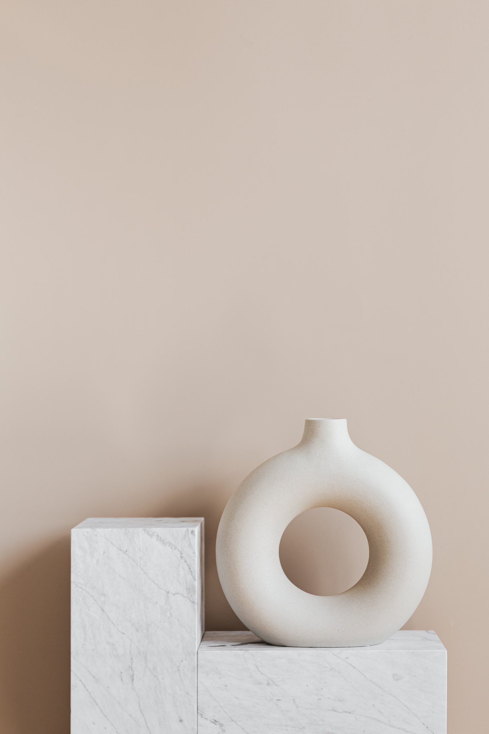 vase oval sur bloc de marbre devant un mur crème