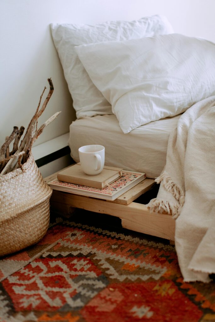 lit style boho chic sur planches en bois avec tapis coloré et tasse de café